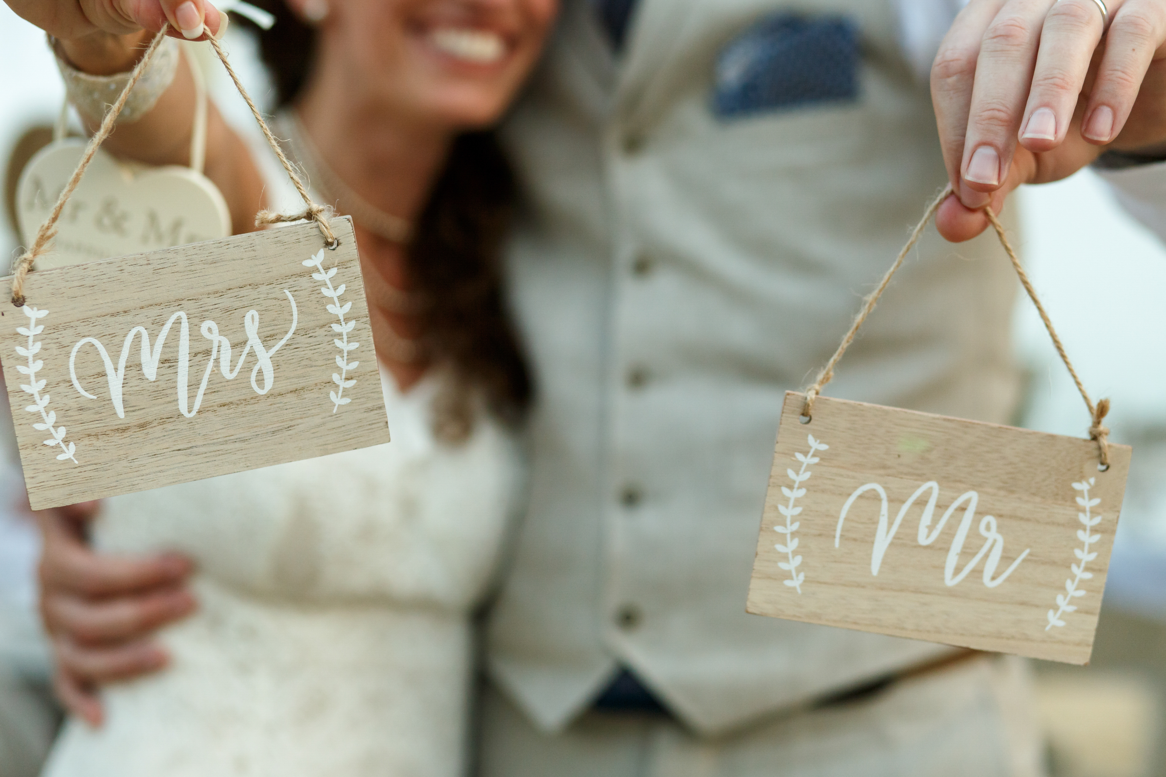 Happy newlyweds hold wooden boards with letterings 'Mrs' and 'Mr